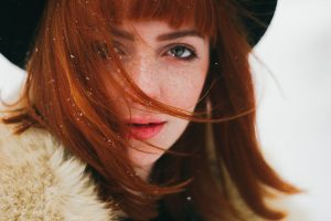 permanent red hair dye uk, woman with red bobbed hair wearing black hat and fur collared coat