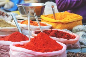 image of brightly coloured red powders in small cloth bags, with image of a yellow one in the distance alongside a stainless steel bowl