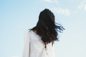 organic black hair dye, woman wearing white with long black hair hanging over her face