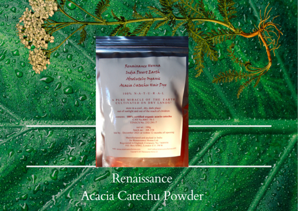 copper hair dye acacia catechu in sealed foil packet with white label, displayed against a green plant background