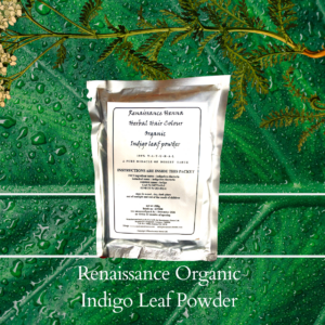 natural black hair dye product image of sealed foil packet of organic indigo powder, displayed against a green plant background and flower