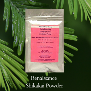 shikakai hair wash powder in a foil sealed packet with pink label, displayed against a green leaf background