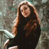 with long hair perched against a balcony railnatural auburn brown hair dye on lady