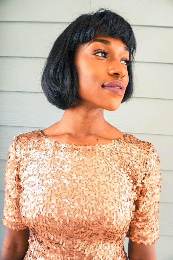 herbal hair colouring with henna indigo; beautiful black woman wearing glittery gold dress, sporting short straight bob haircut