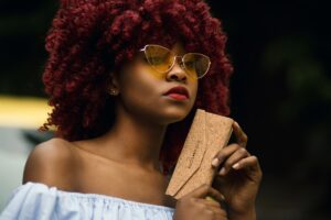 chemical free organic henna hair dye in natural wavy hair on lady wearing off the shoulder white top and sunglasses