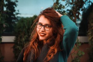 woman wearing glasses with long wavy auburn red natural hair colour, hair dyed