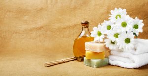natural cleansers for hair and body, photo of natural soaps alongside a bunch of white flowers and a bottle of cidar vinegar for hair rinsing