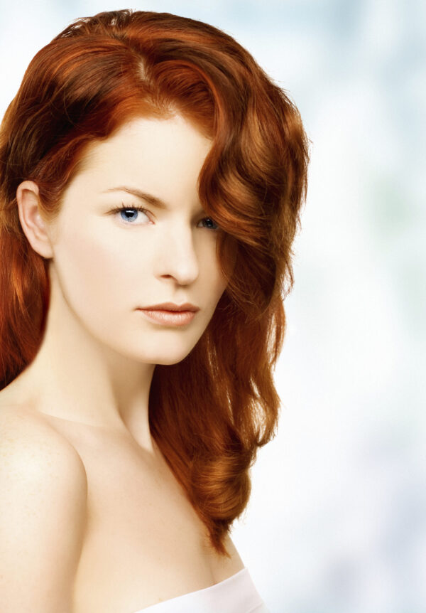 organic henna hair dye on beautiful red head with long wavy hair flowing over one shoulder, wearing a white towel covering upper part of her body