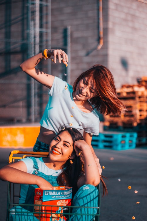 dark natural hair dye from henna & indigo colours auburn, brown and black; picture of two women playing with a shopping trolley, one pushing the other, one with dark red hair and the other with dark brown hair