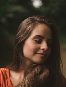 Organic amla oil for healthy hair ; woman with brown ahir brushed to one side, eyes closed, 