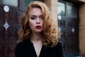 Organic strawberry blonde; woman wearing black with shoulder length, wavy, strawberry blonde colour hair