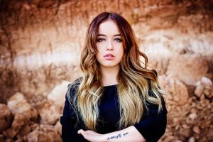 rhassoul clay skin clay from Morocco, beautiful woman with long dark blonde hair standing in a field