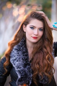 henna with add ins on light brunette hair colour, photo of woman with long soft brown hair wearing a black coat with grey fur collar 