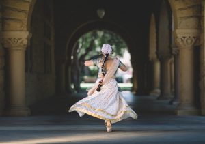 Henna hair colour journey, Indian lady in traditional costum ewith long hair plait hanging down her back, dancing under a shaded arch