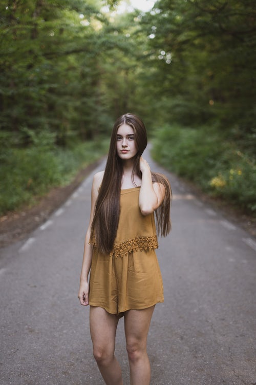amla natural hair care, woman standing on road in forest with beautiful healthy long brown hair