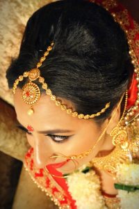 Black Natural Hair Colour close up of Beautiful Asian Woman wearing bridal make up and gold hair jewellery