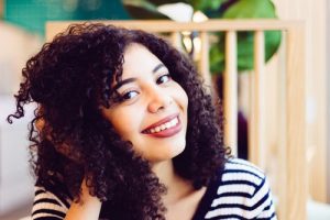 Indigo mixed with henna: Mix indigo with henna for a one step henna hair colour application, lady in stripey T shirt with natural wavy hair, dark hair colour with lowlight glints of henna red