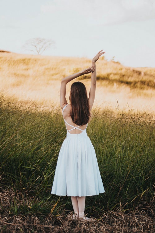 Allergy Patch Testing, picture of woman in white dress standing in a field, arms raised, back exposed