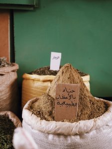 Plant based products for natural hair colour , image of henna powder in a sack in a room full of other plant based commodities