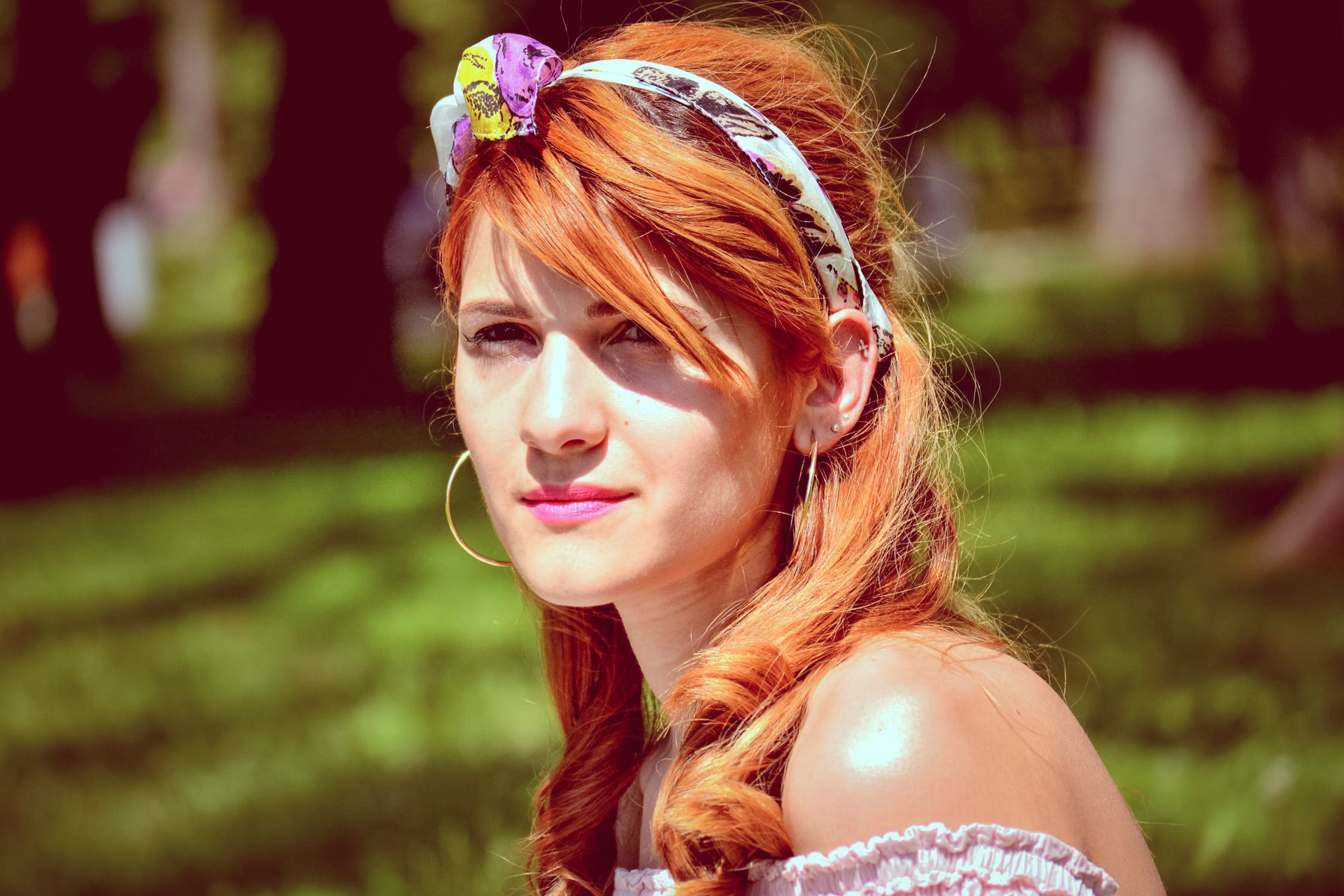 Acacia Catechu is a semi permanent hair dye which gives Copper highlights on Blonde hair.: Lady Sitting in the Sunshine with Copper Coloured Hair Secured by Colourful Headband, and Fringe Falling Across Her Face