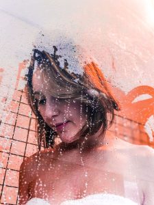shampoo v natural shampoo, woamn washing her hair in the shower, lather in her hair